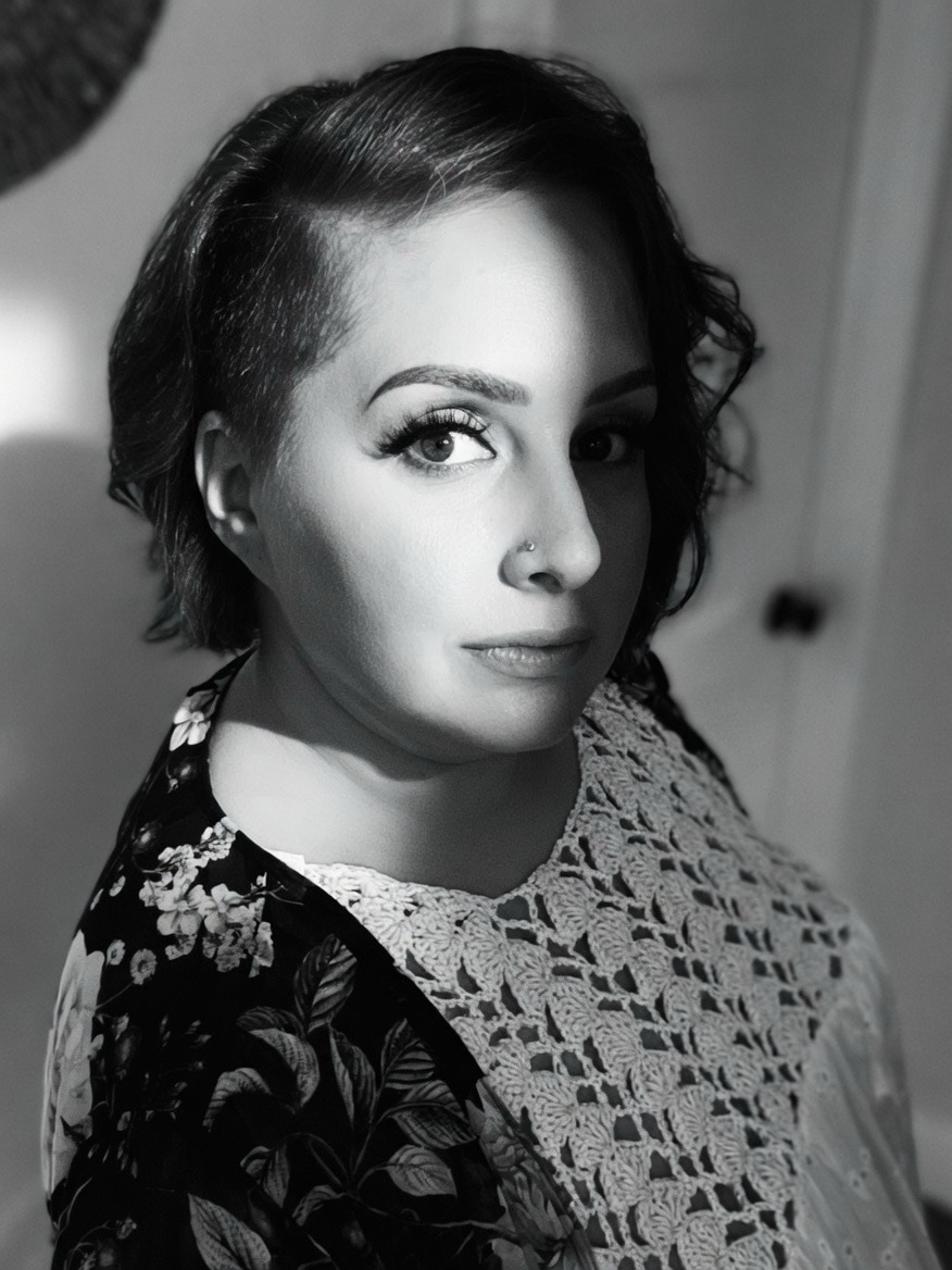 Samantha Lucia, black-and-white portrait, turned over one shoulder toward the camera, wearing a floral print and a lace shawl.